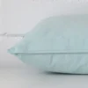 Horizontal edge view of front and back panels of a velvet cushion in a rectangle size and with duck egg colouring.