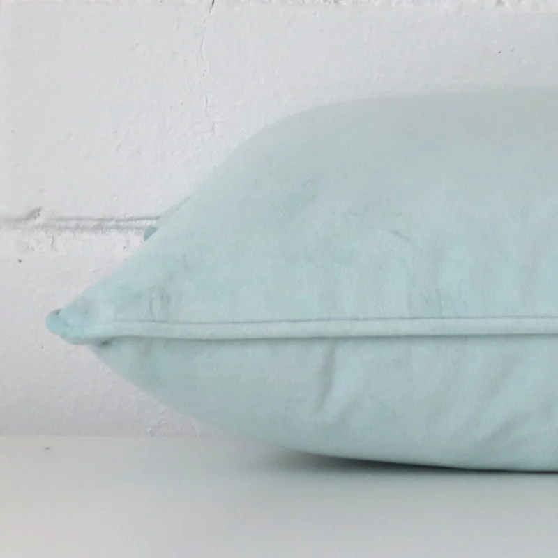 Horizontal edge view of front and back panels of a velvet cushion in a rectangle size and with duck egg colouring.