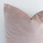 The corner of this velvet square cushion cover is shown close up. The solid dusty pink colour is shown in greater detail.