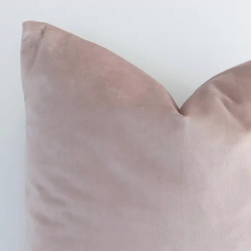 The corner of this velvet square cushion cover is shown close up. The solid dusty pink colour is shown in greater detail.