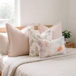 Set of four cushions with blush linen, a floral print, and a watercolour lumbar, on a bed.