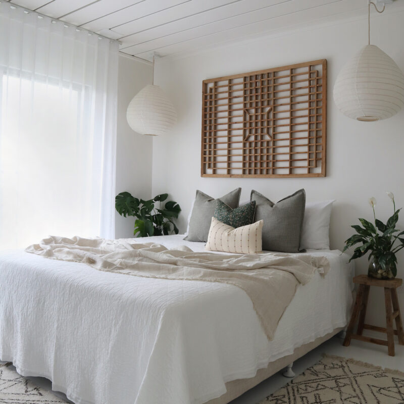 A bed with 4 designer bed cushions in a bright room.