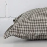 Lateral angle image of a designer large cushion. The colour and gingham design are highlighted along its seams.