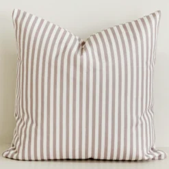 Dusty pink striped cushion cover on cream cotton-linen base.