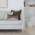 A corner of a grey sofa with the two designer cushions from the Eliza sofa cushions styled on it.