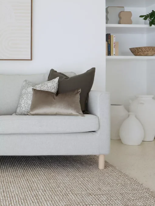 A corner of a grey sofa with the two designer cushions from the Eliza sofa cushions styled on it.