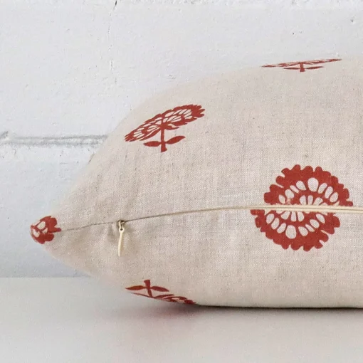 The seams of this linen rectangle cushion cover in rust are shown. The image shows the floral design and how the panels are attached.