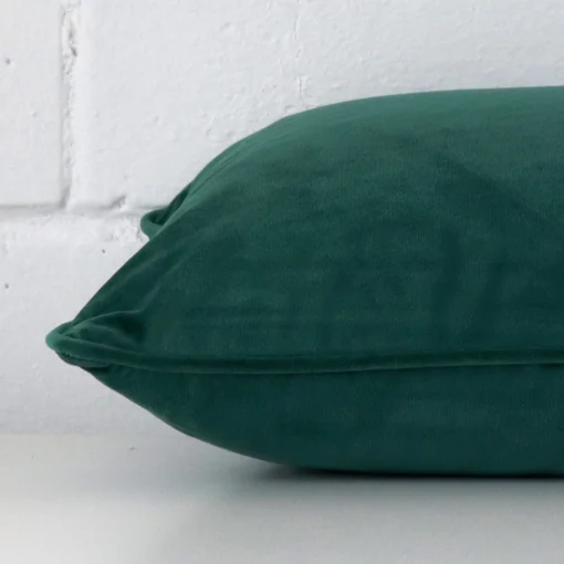 Side shot showing the seam of this rectangle emerald green cushion that is made from a velvet material.