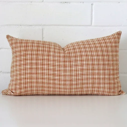 A rectangle gingham cushion in a delightful tone rests against a white wall. The designer material appears to be of exceptional quality.