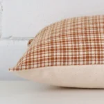 A gingham cushion cover is laid flat. This angle shows the side of the gingham fabric and its rectangle shape.