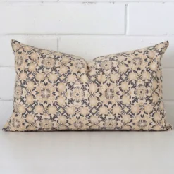 A brick wall that has a cushion cover positioned in front of it. It has an exquisite designer material and a lovely rectangle shape.