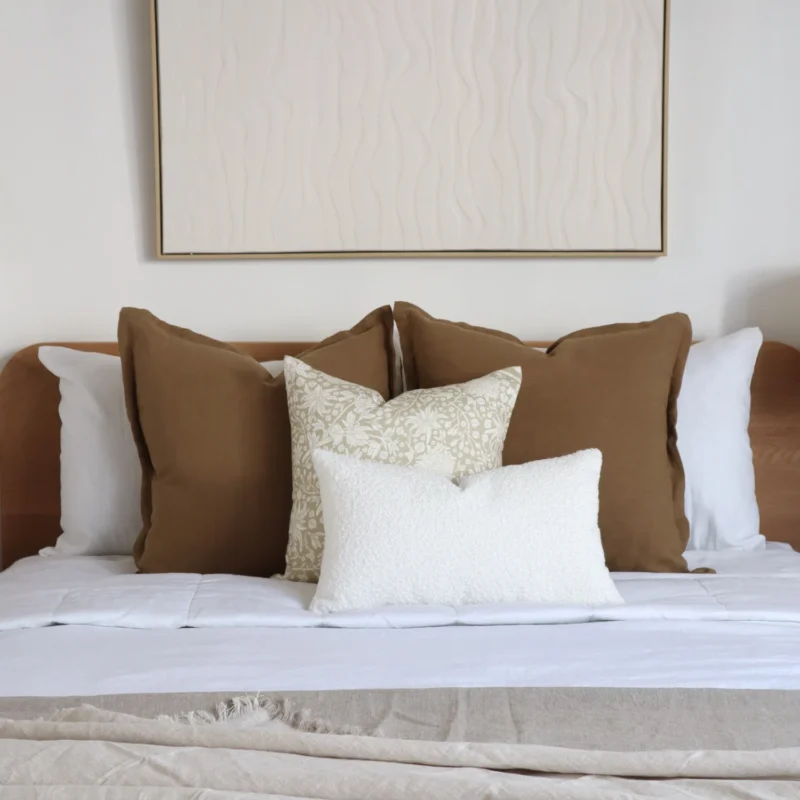 A wooden bed with a set of 4 cushions sits on it.
