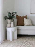 Two cushions from the set of five Eve sofa cushions on a corner of a light grey sofa.