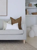 A corner of a grey sofa is styled with the three designer cushions from the Eve sofa cushions set.