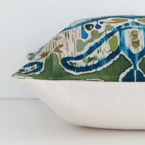 Side perspective showing seam of square colourful cushion cover that has a patterned motif on its linen fabric.