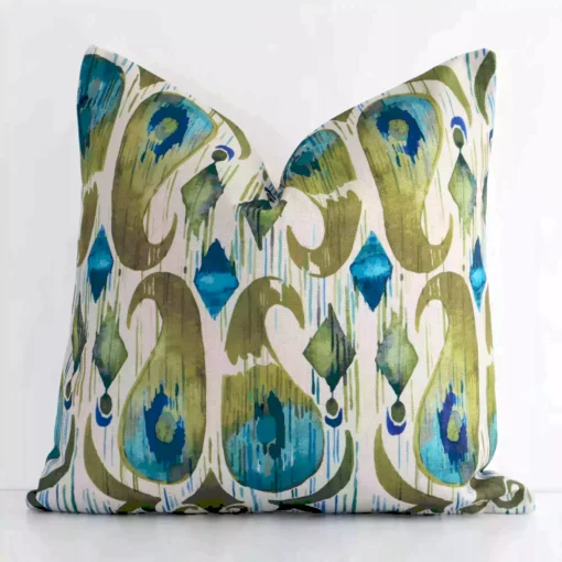 An attractive patterned linen cushion in front of a white wall. It has a square shape and is colourful.