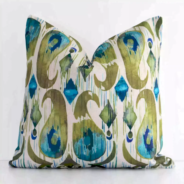 An attractive patterned linen cushion in front of a white wall. It has a square shape and is colourful.