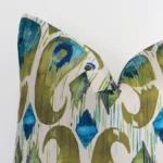 Macro shot showing the top left side of this square linen cushion. The colourful hue and patterned design are magnified.