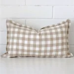 A pretty gingham designer cushion cover is shown against a brick wall. It features a rectangle shape.