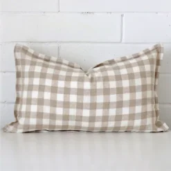 A pretty gingham designer cushion cover is shown against a brick wall. It features a rectangle shape.