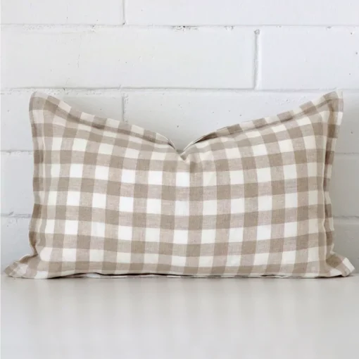 A pretty gingham designer cushion cover is shown against a brick wall. It features a rectangle shape.