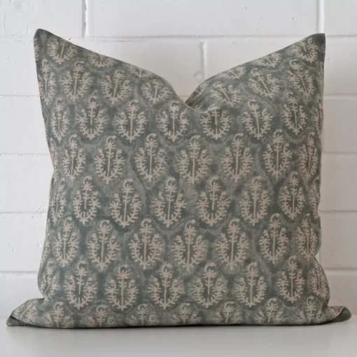 A large cushion rests against a white wall. The designer material appears to be of exceptional quality.