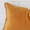 A velvet rectangle cushion’s corner has been enlarged in this shot. It has a gold mustard colour.