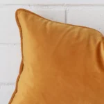 A velvet rectangle cushion’s corner has been enlarged in this shot. It has a gold mustard colour.