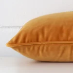 Lateral angle image of a velvet rectangle cushion. The gold mustard colour is highlighted.