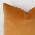 A magnified shot of a velvet cushion cover in a large size and a gold mustard colour.
