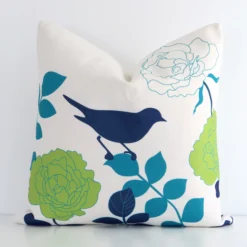 Colourful paterned cushion cover sits against a white wall. It is constructed from a superior looking linen material and has square shape.