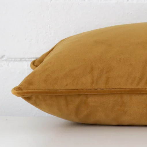 Enlarged image of the side of this honey mustard velvet cushion. The angle highlights the edge of its rectangle design.