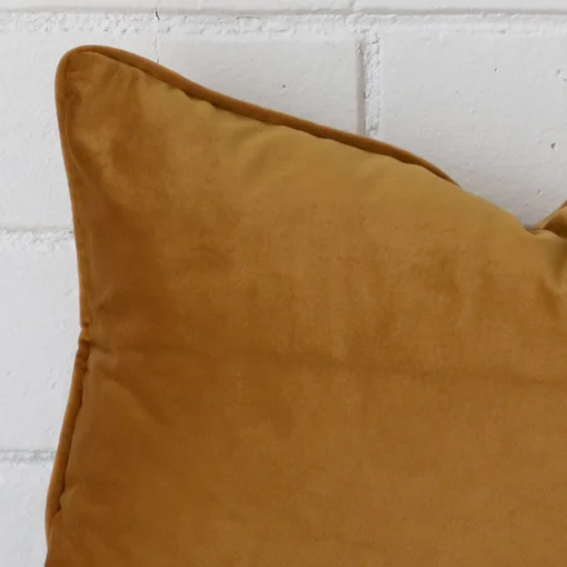 A honey mustard velvet cushion cover’s corner is shown in more detail.