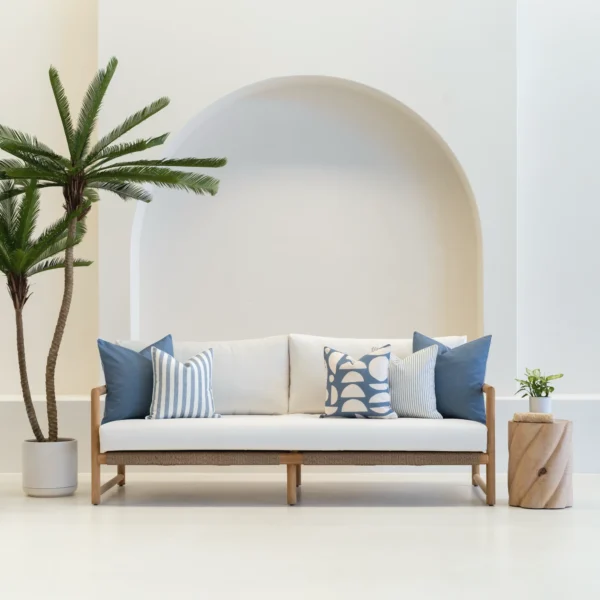 A wooden sofa is styled with a set of 5 horizon blue outdoor cushions.