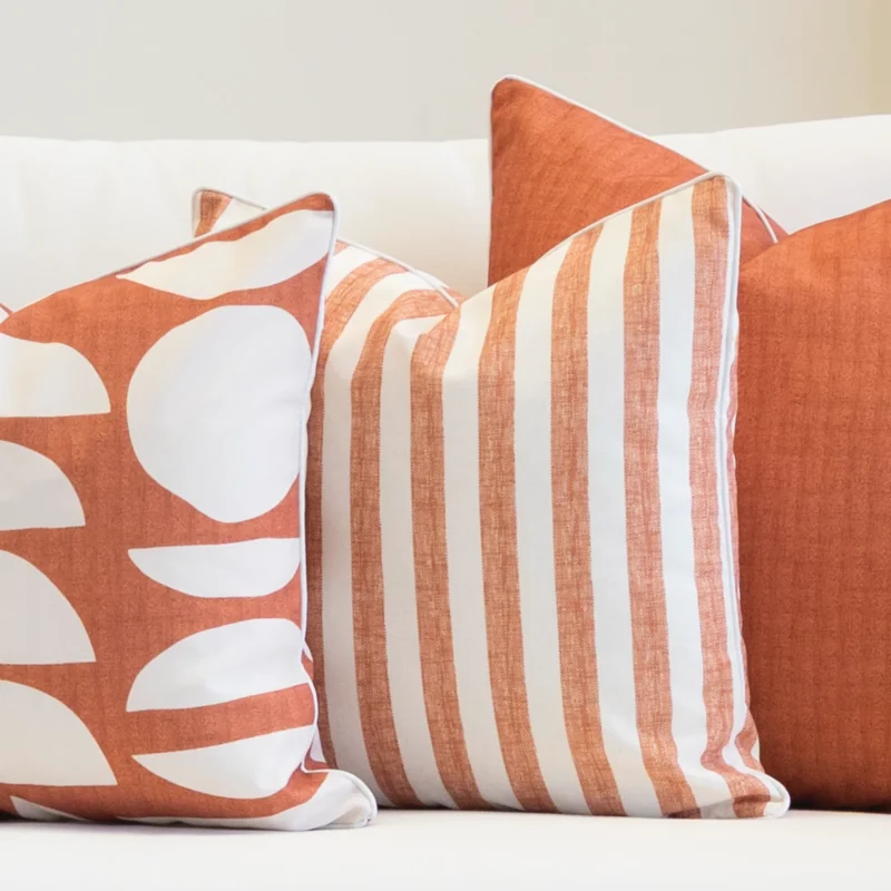 The horizon rust set of 3 sofa cushions is styled on a white couch.