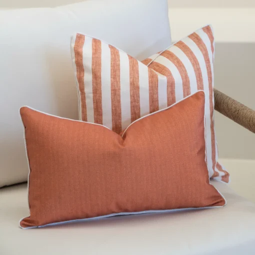 White sofa with 2 horizon rust outdoor cushions carefully arranged on it.
