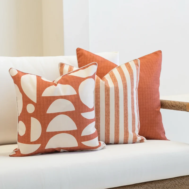 3 horizon rust outdoor cushions displayed on a white sofa.