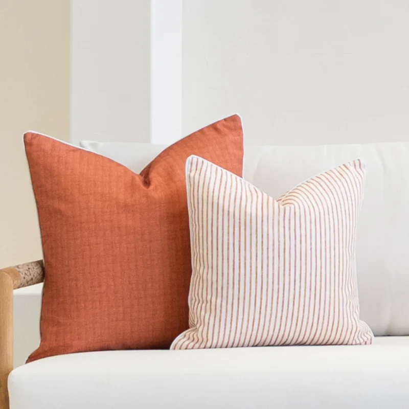 2 horizon rust outdoor cushions displayed on a white sofa's corner.