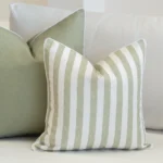 A white sofa styled with a set of 2 horizon sage outdoor cushions.