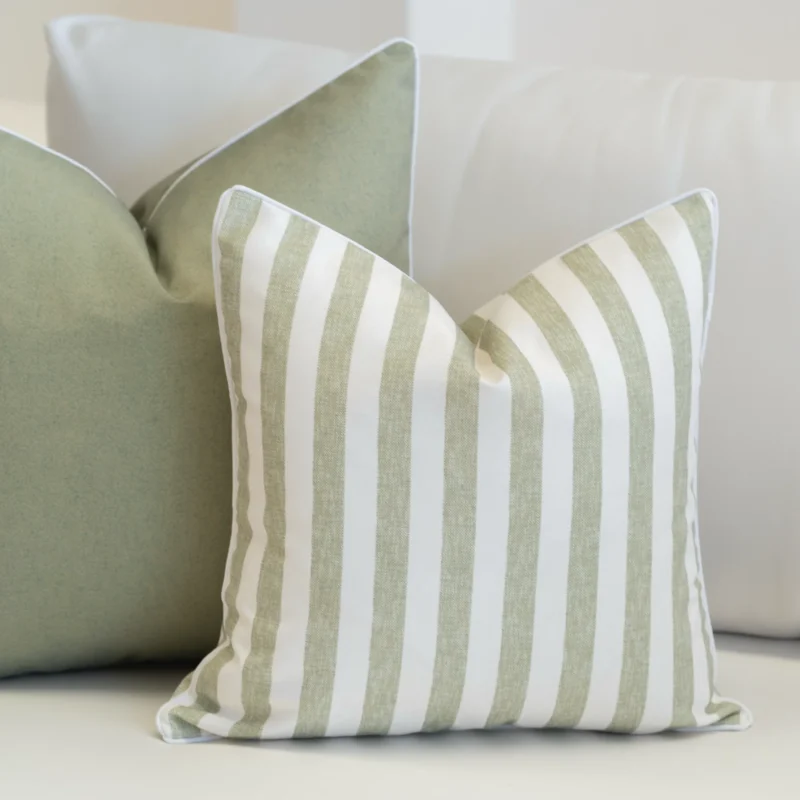 A white sofa styled with a set of 2 horizon sage outdoor cushions.