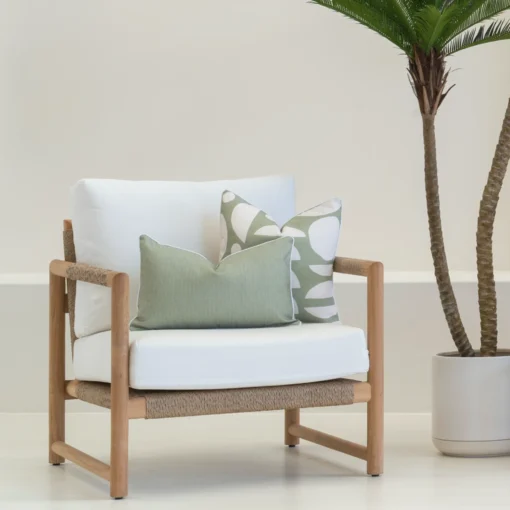 A set of 2 horizon sage outdoor cushions sitting on a white armchair.