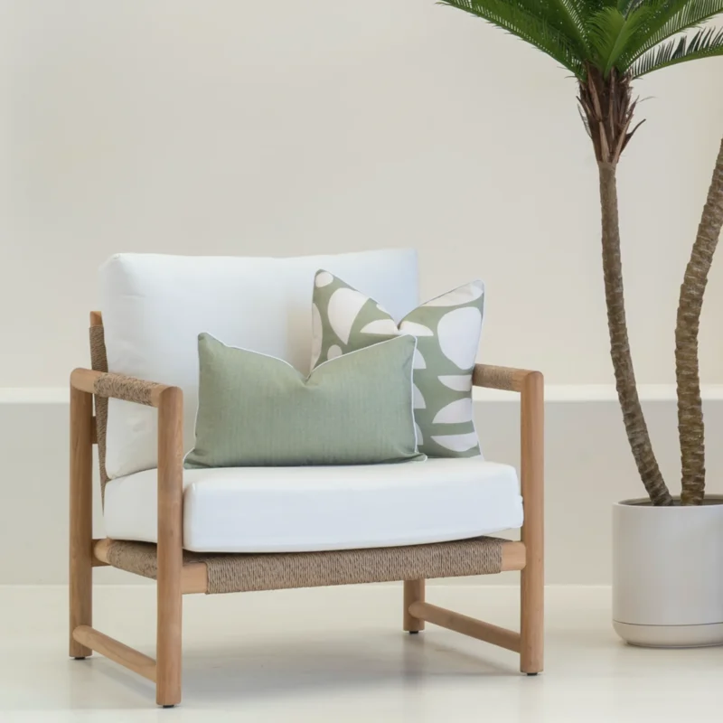 A set of 2 horizon sage outdoor cushions sitting on a white armchair.