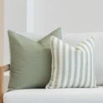 Outdoor seating showcasing a set of 2 horizon sage outdoor cushions on a white sofa.