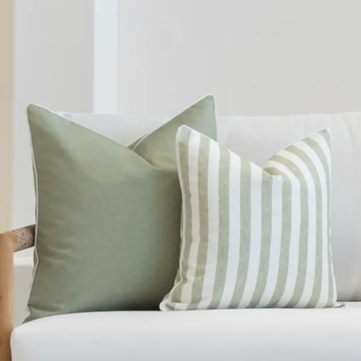 Outdoor seating showcasing a set of 2 horizon sage outdoor cushions on a white sofa.