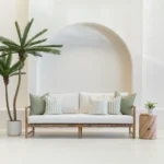 A white sofa is styled with a set of 5 horizon sage outdoor sofa cushions.