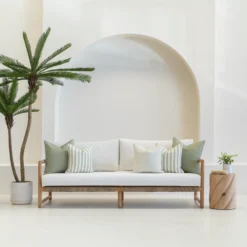 A white sofa is styled with a set of 5 horizon sage outdoor sofa cushions.