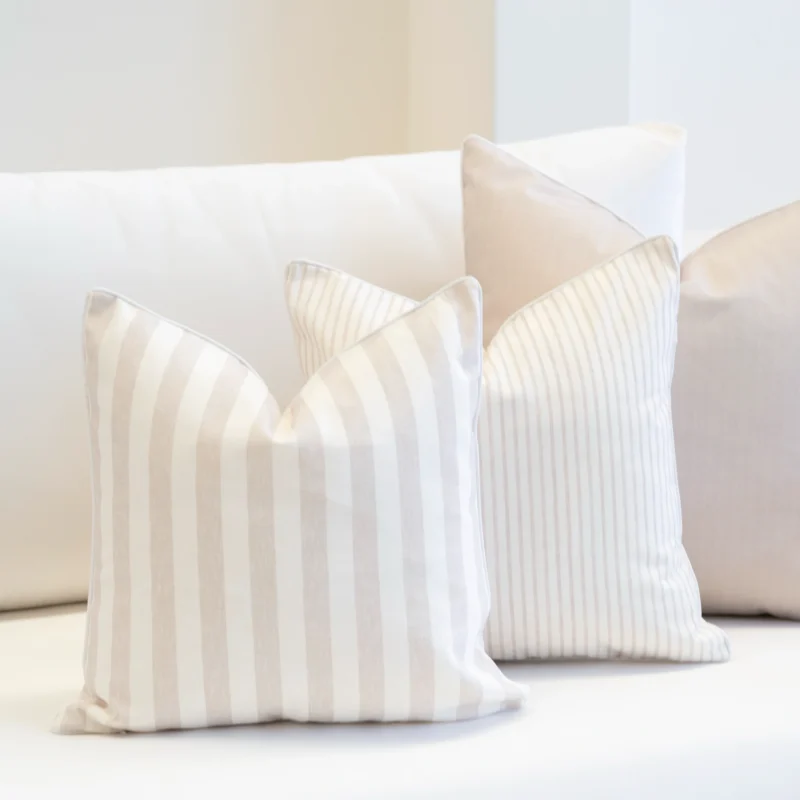 The set of 3 horizon sand outdoor cushions are displayed on a white sofa.