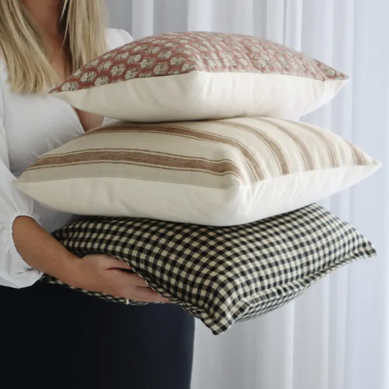 An interior designer is holding a cushion set which contains various styles.