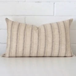 Striped cushion positioned in front of a brick wall. It has rectangle dimensions and is made from a designer material.