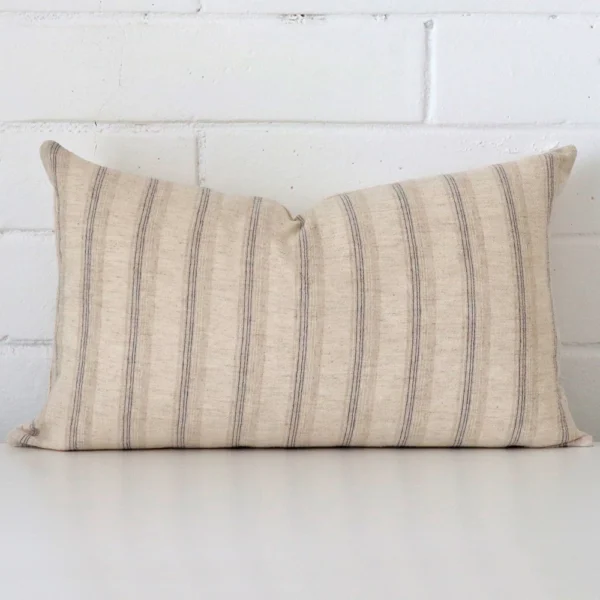 Striped cushion positioned in front of a brick wall. It has rectangle dimensions and is made from a designer material.